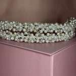Close-up of a bridal headband with pearls and clear crystals in a floral cluster design on a blush pink box.