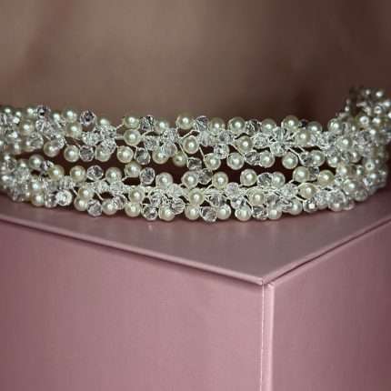 Close-up of a bridal headband with pearls and clear crystals in a floral cluster design on a blush pink box.