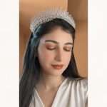 Woman wearing a silver crystal bridal tiara crown with a tall, sparkling silhouette.