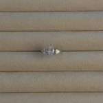 Close-up of Tears of Joy Bridal Set ring featuring a pear-cut cubic zirconia center stone with side accents in a rhodium-plated finish on a beige jewelry tray.