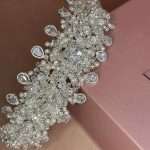 Angled view of Eternal Pearl Shine bridal headband featuring ivory pearls, clear crystals, Swarovski sparkle, and CZ teardrop drops on a blush box.