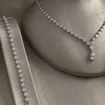 Close-up of Tears of Joy Bridal Set showing a rhodium-plated cubic zirconia pear-drop necklace with teardrop pendant and a matching tennis bracelet on a silver display.