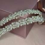 Diagonal close-up of a pearl and clear crystal bridal headband with floral clusters .