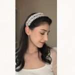 Side profile of a model wearing a floral pearl and clear crystal bridal headband with soft waves.