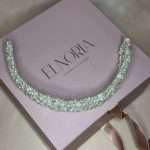 Pearl and clear crystal bridal headband displayed in a curved flat lay on a pink Elnoria gift box.