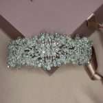 Top-view of a wide statement bridal headband with pearls, clear crystals, Swarovski accents, and cubic zirconia on a pink gift box.