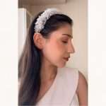 Side profile of a woman wearing a pearl and clear crystal bridal headband with sparkling clustered detail