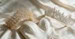 Elnoria Bronze Bloom gold tiara and the silver Swarovski crystal tiara laid on ivory silk